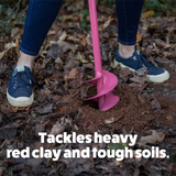 Person using a pink gardening tool to break up soil in a garden bed.